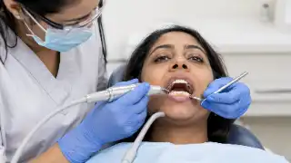 Professional Dental Hygienist Performing Teeth Scaling on Patient in Clinic
