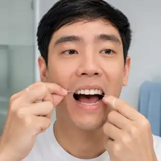 Asian Man Flossing Teeth Daily For Good Oral Hygiene Stock Photo