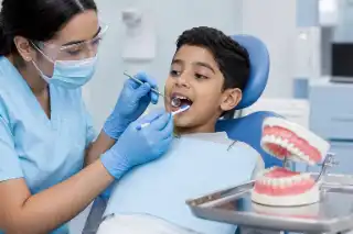 Pediatric Dentist Examining Young Boy Teeth in Dental Clinic